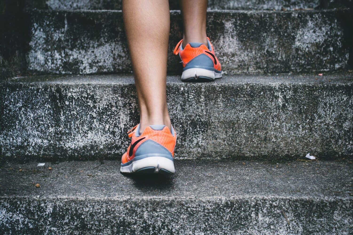 Parte inferiore delle gambe di una persona che sale le scale, ottimizzando l'azione di camminare per dimagrire.